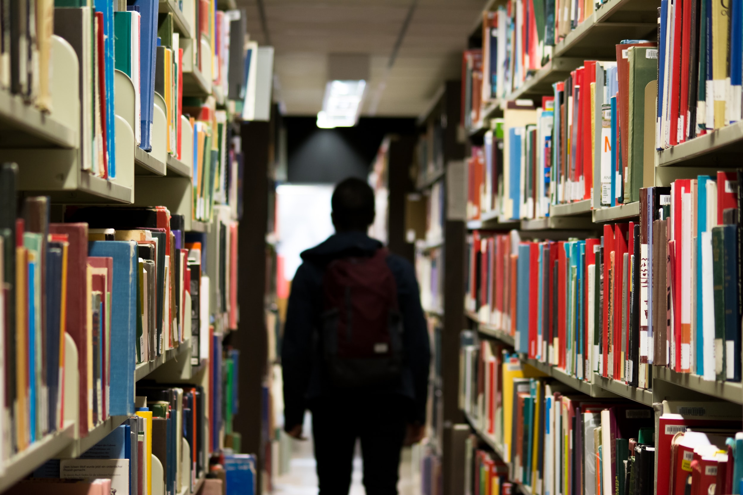 A student walking between library shelves.