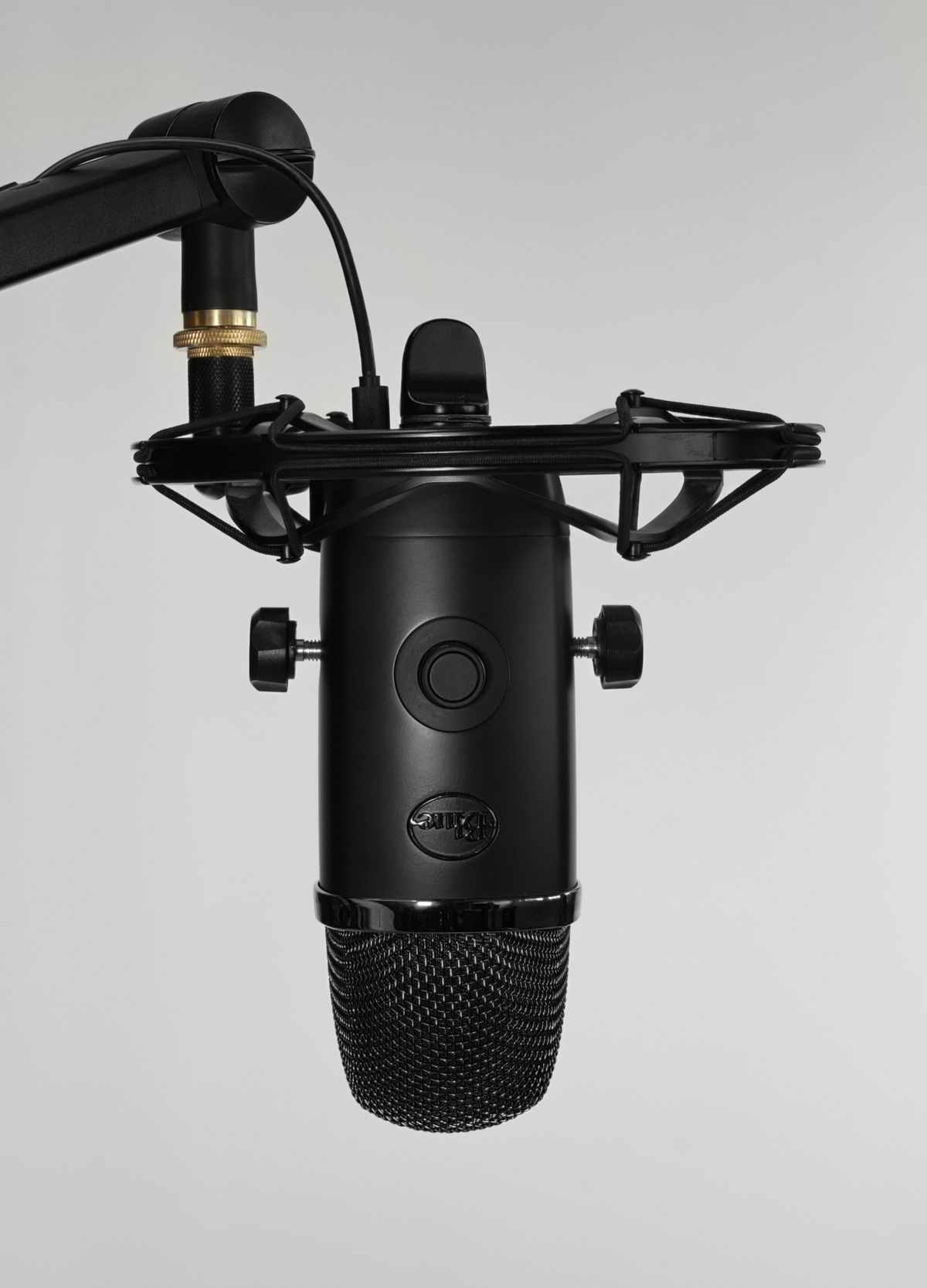 A black Yeti microphone on a boom arm with shock mount.