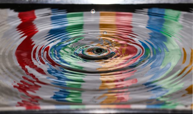Ripples on top of water with a rainbow pattern reflected.